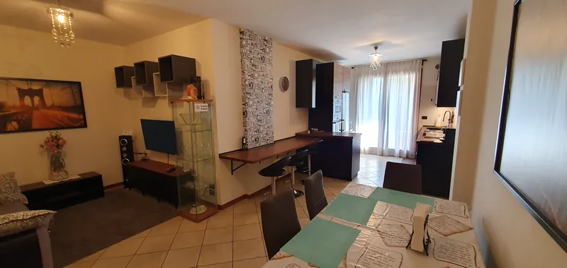 Soggiorno aperto sulla cucina, con tavolo da pranzo e penisola